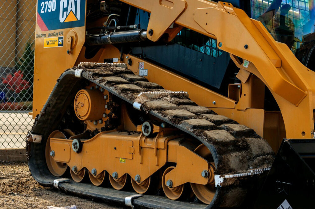 rubber skidsteer track rolling along dirt terrain with silver rubbergrip excavator attachments for improved traction