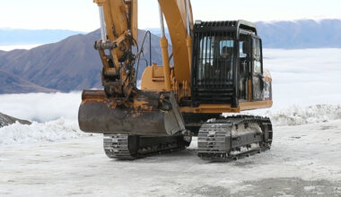 Excavator track rolling across ice with icegrip snow traction device attached