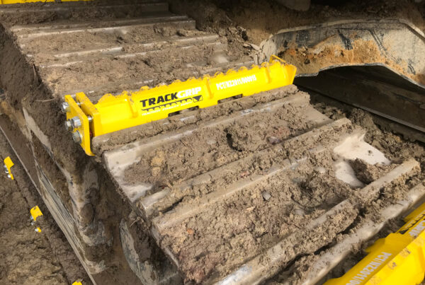 steel excavator track rolling along a dirt terrain with yellow mightygrip excavator track attachments