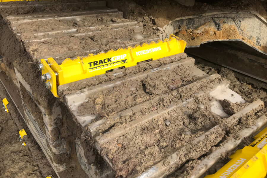 steel excavator track rolling along a dirt terrain with yellow mightygrip excavator track attachments
